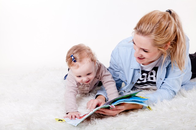 Babysitterin schaut mit Baby in ein Buch
